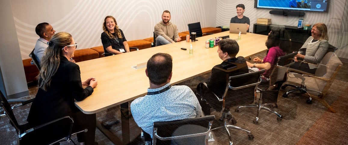 Six EMHA students sit around a boardroom table and speak with Fullscript CEO Kyle Braatz and Program Associate Director Karen Nelson at Fullscript office. 