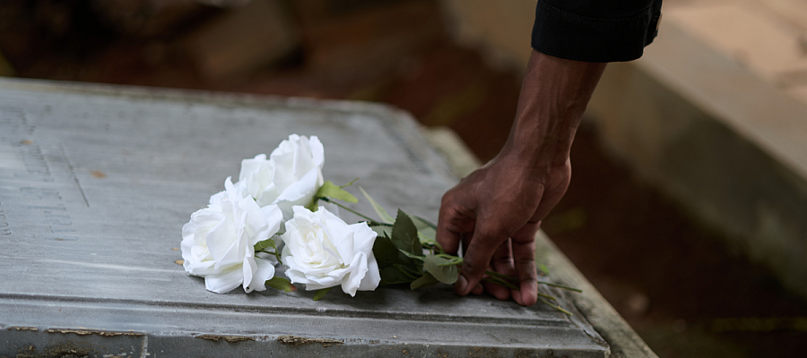 person placing flowers on a grave