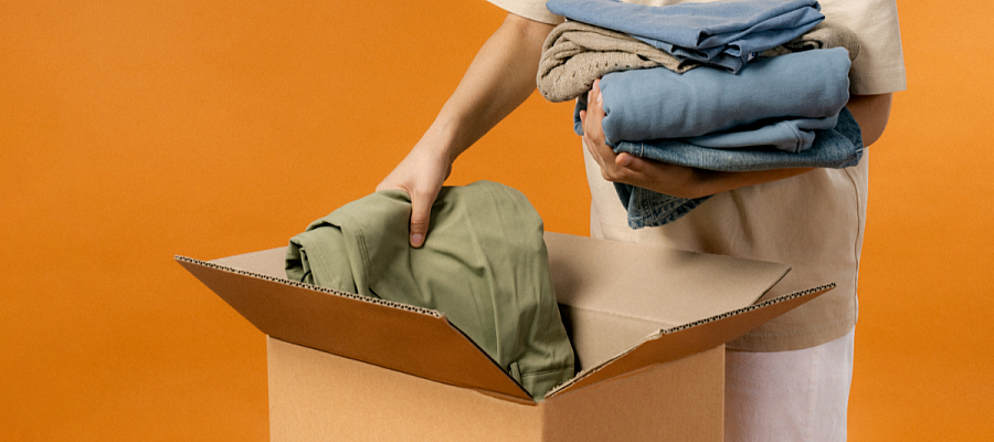 photo d'une personne rangeant des vêtements dans un carton pour les donner