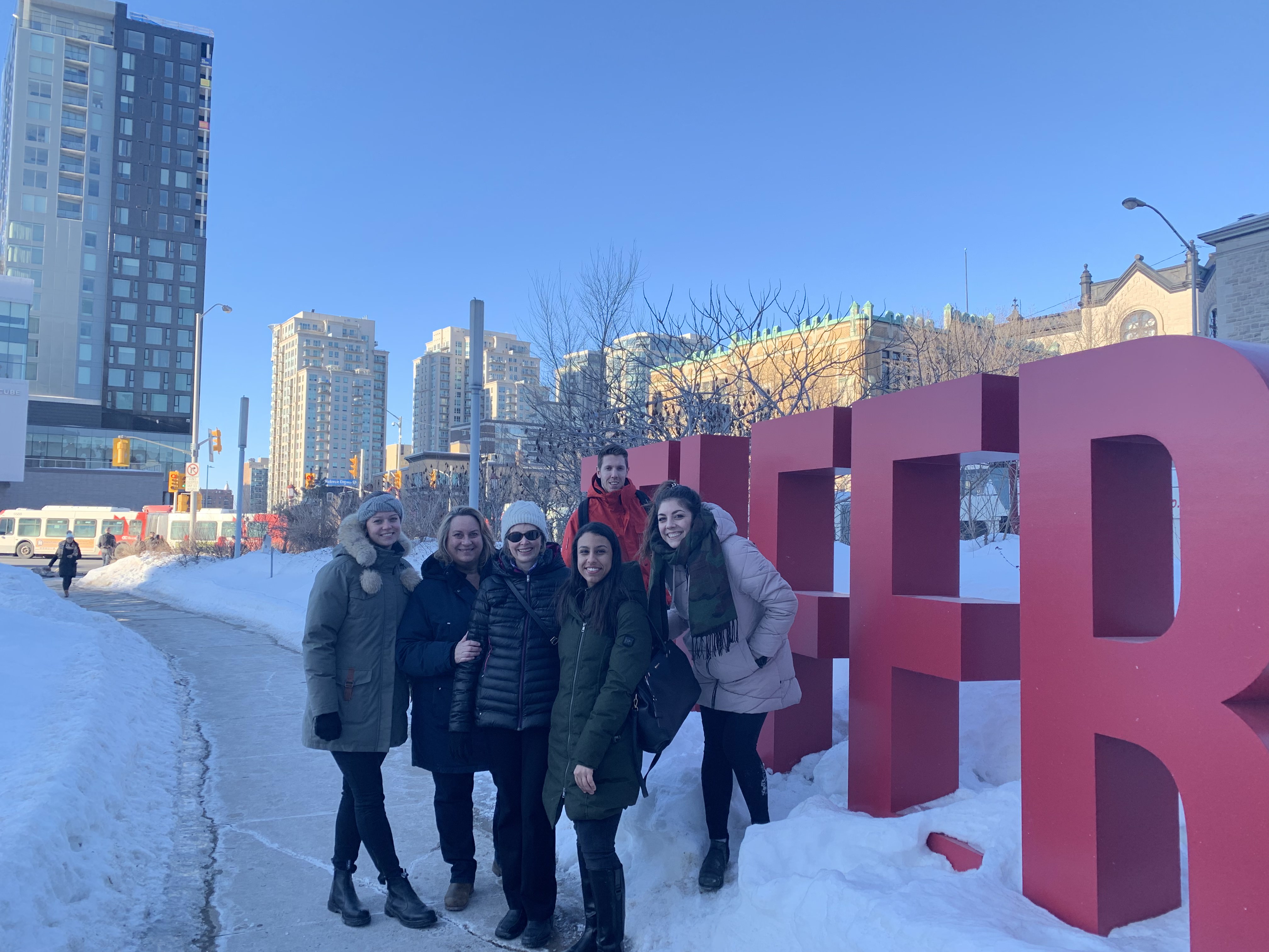 People smiling in front of outdoor Telfer letters