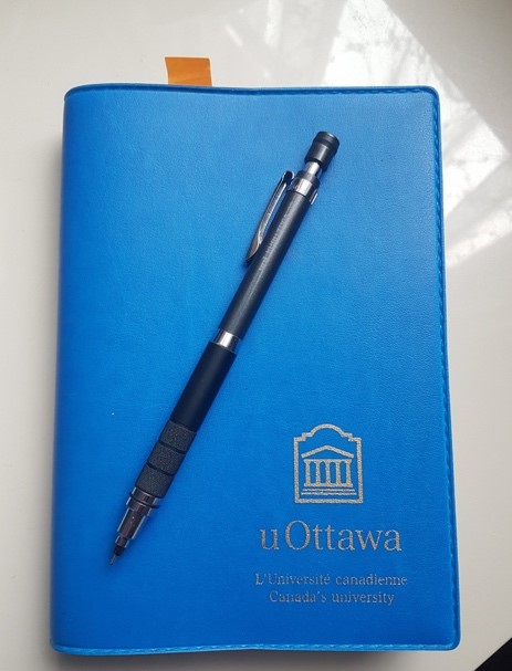 Agenda bleu de l'uOttawa sur le bureau avec stylo