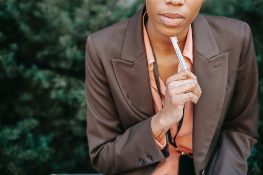 The lower part of a woman's face in listening interview mode with a pencil under her chin 