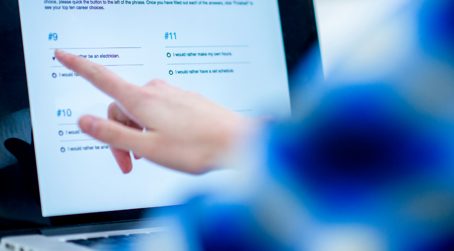 student pointing to their computer screen displaying an online quiz