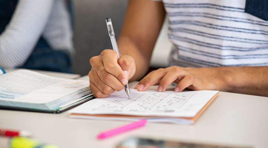 student filling out a multiple-choice exam at a desk