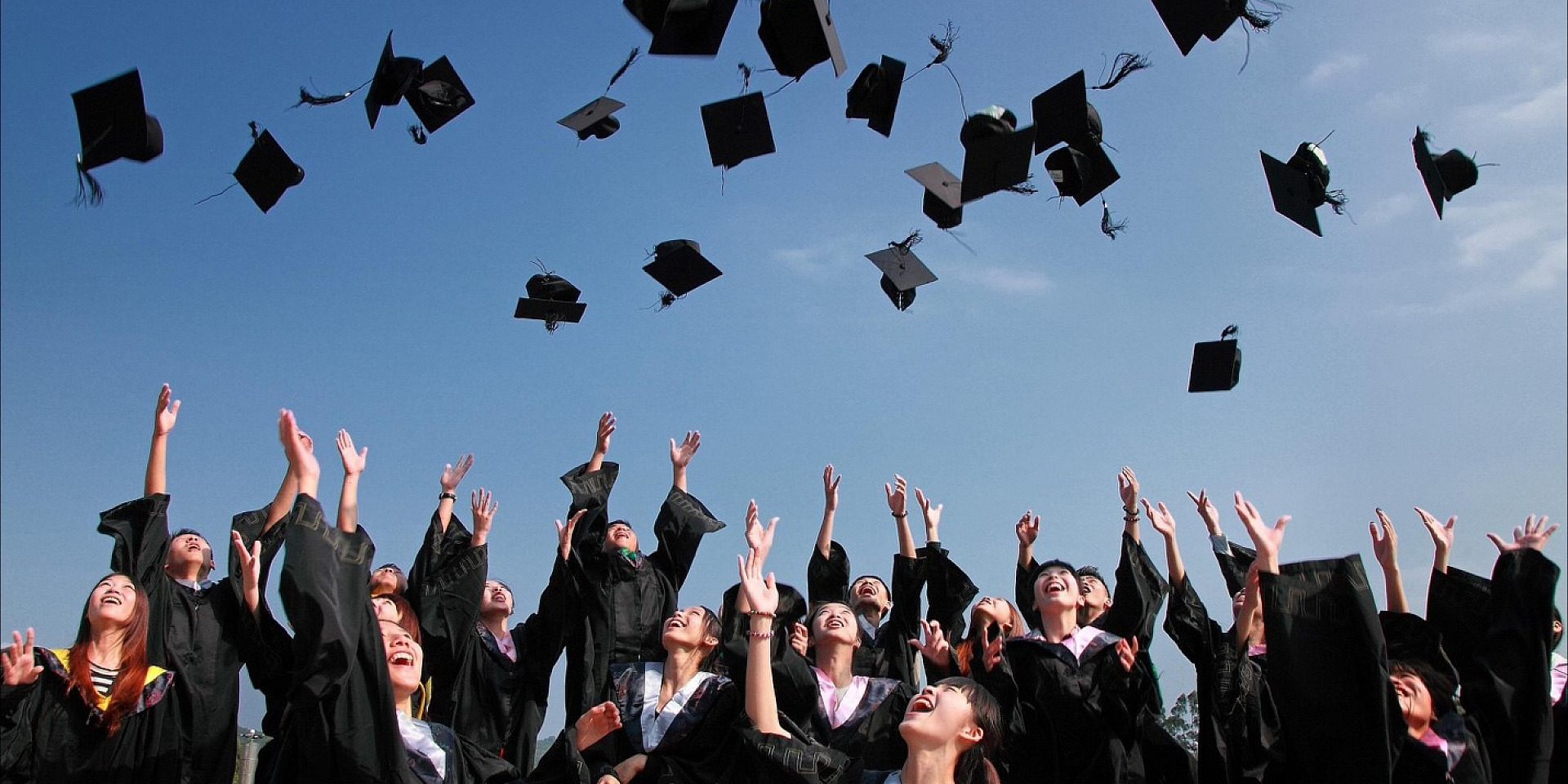 Étudiants lançant leur chapeau de diplômé en l'air par une journée d'été.