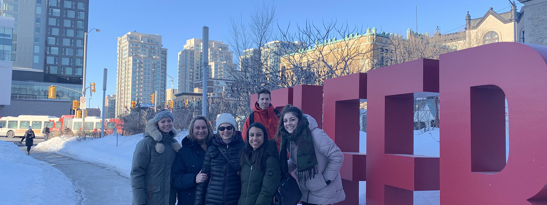 People smiling in front of outdoor Telfer letters
