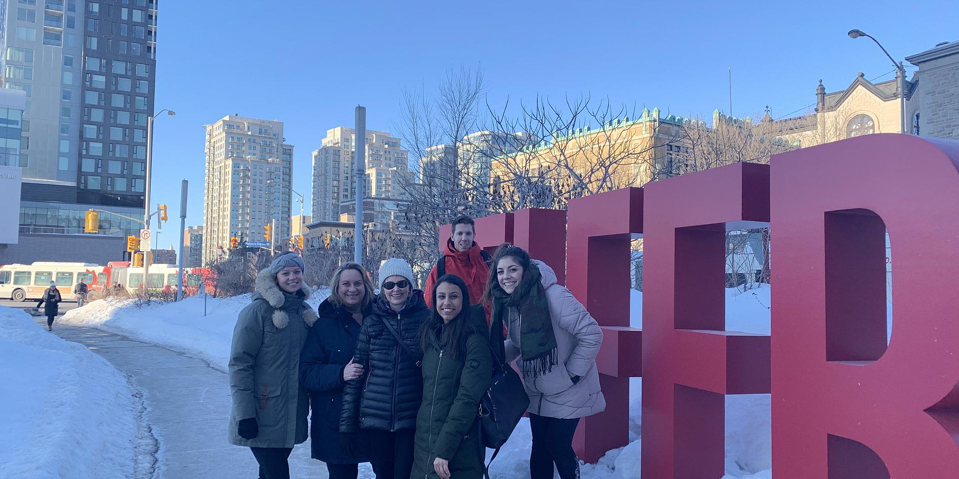 People smiling in front of outdoor Telfer letters