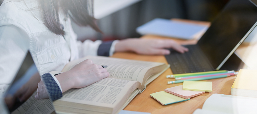 student studying with textbook and tablet