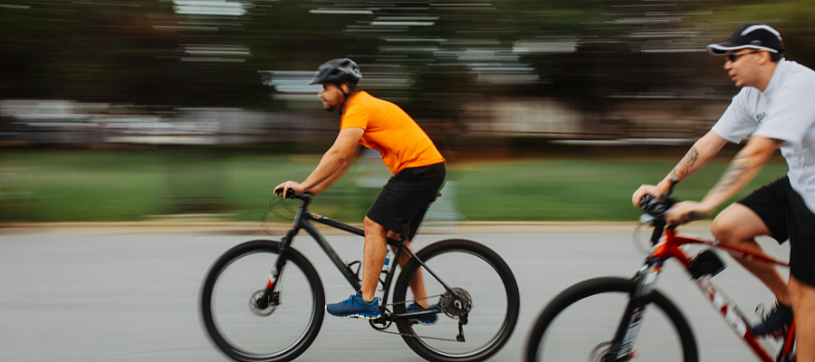 Two people riding bicycles on a road, captured in motion, representing active transportation and sustainable mobility.