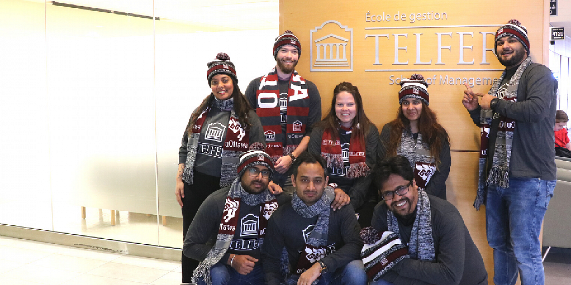 mba games team in front of telfer school of management sign in desmarais building