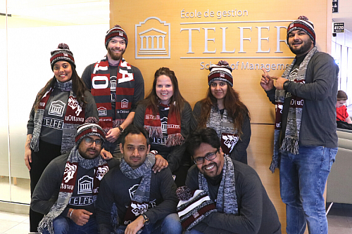 mba games team in front of telfer school of management sign in desmarais building