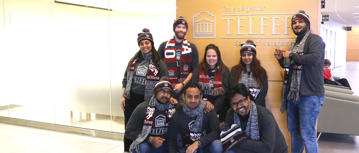 mba games team in front of telfer school of management sign in desmarais building