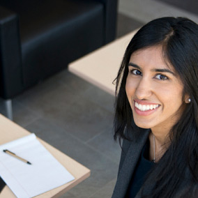 Une étudiante souriante assise à un bureau.