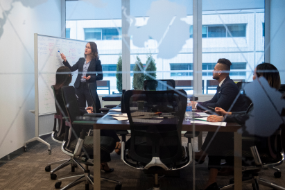 Four Telfer students in a boardroom, one pointing at a whiteboard.