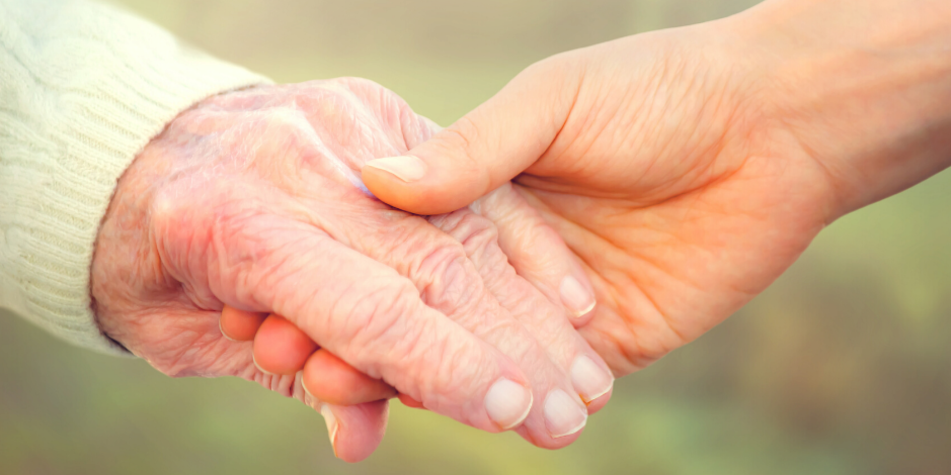 Une jeune personne et une personne âgée se tenant la main
