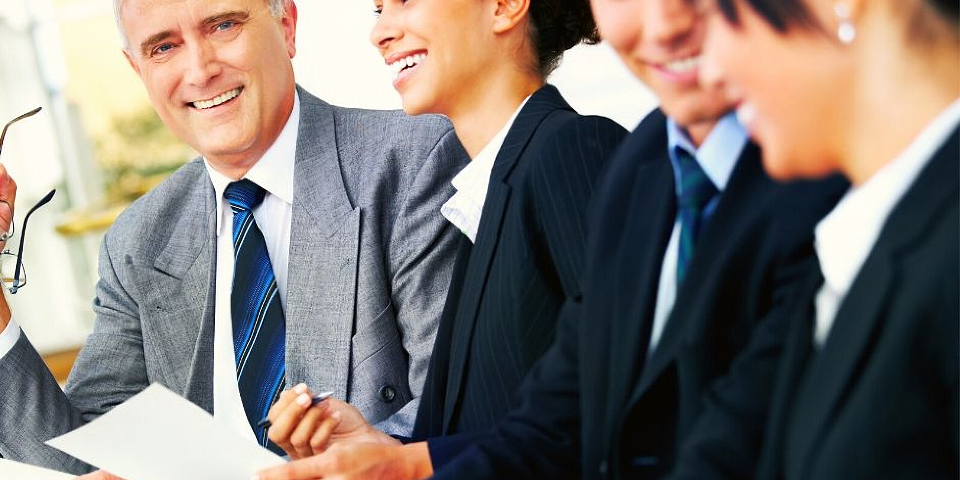 Four business people smiling while sitting together