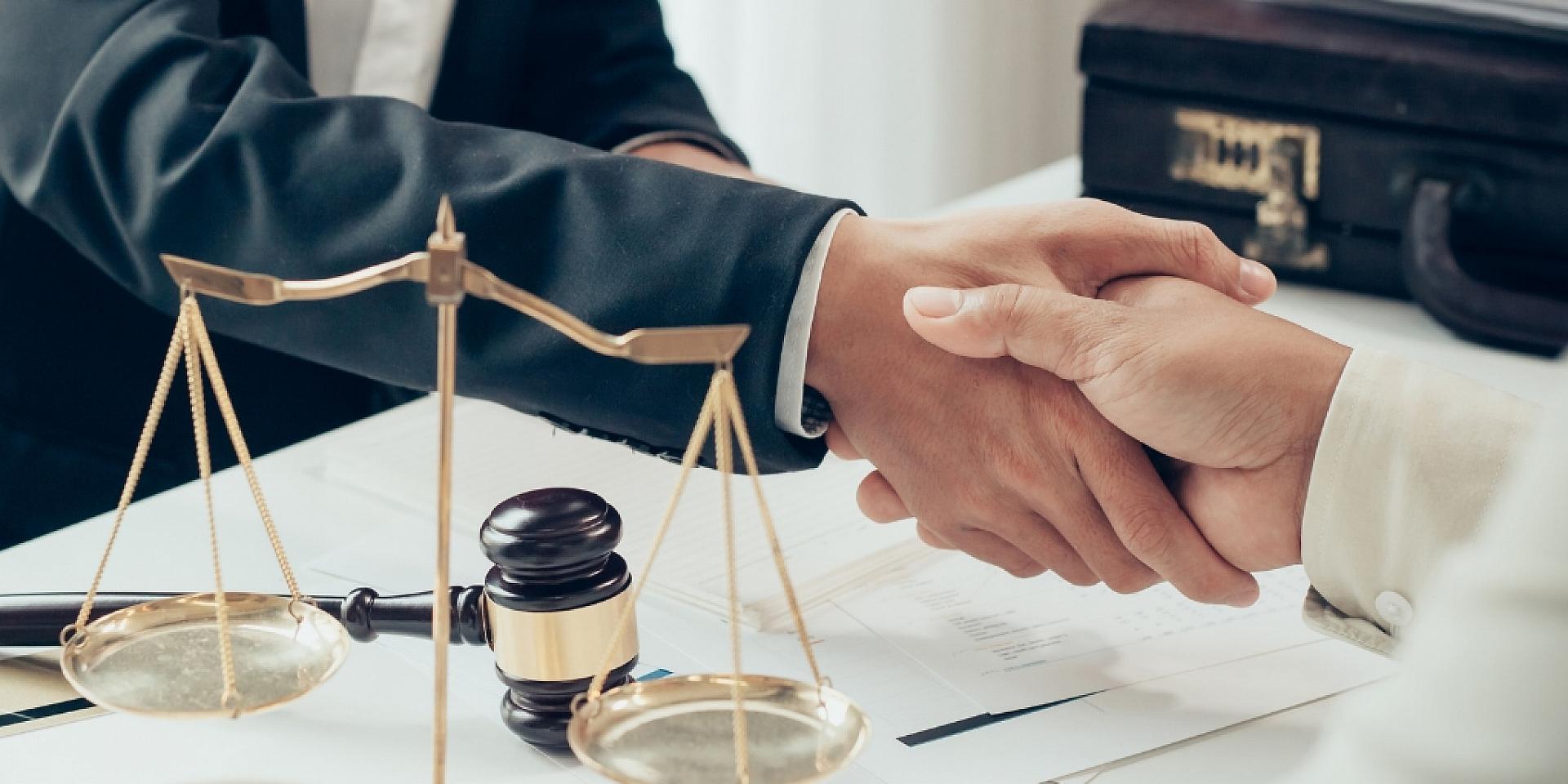 Two people shaking hands with symbolic objects that represent the law