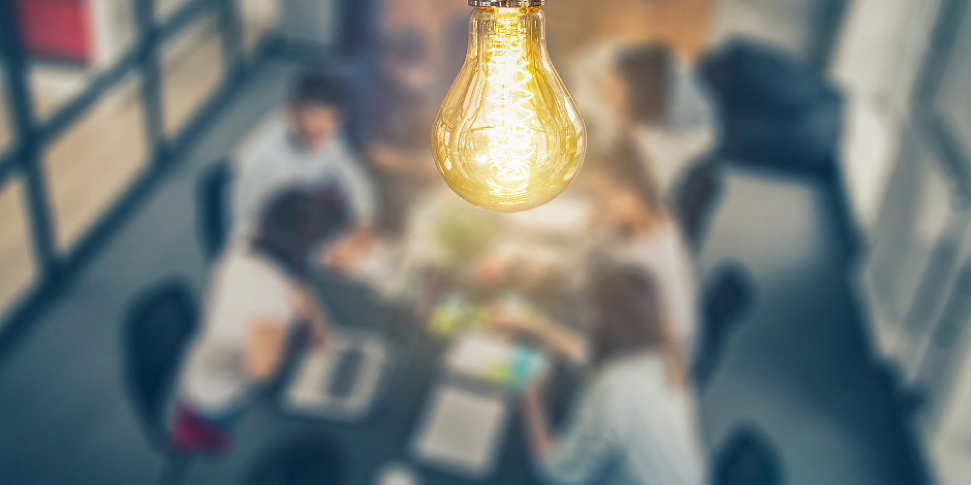 Lightbulb hanging over a group of people having a business meeting